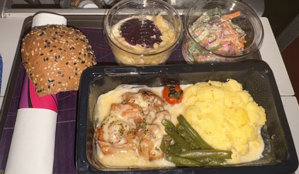 機内食（グリルチキンとチーズポレンタ、サラダ、チーズケーキ、パン）